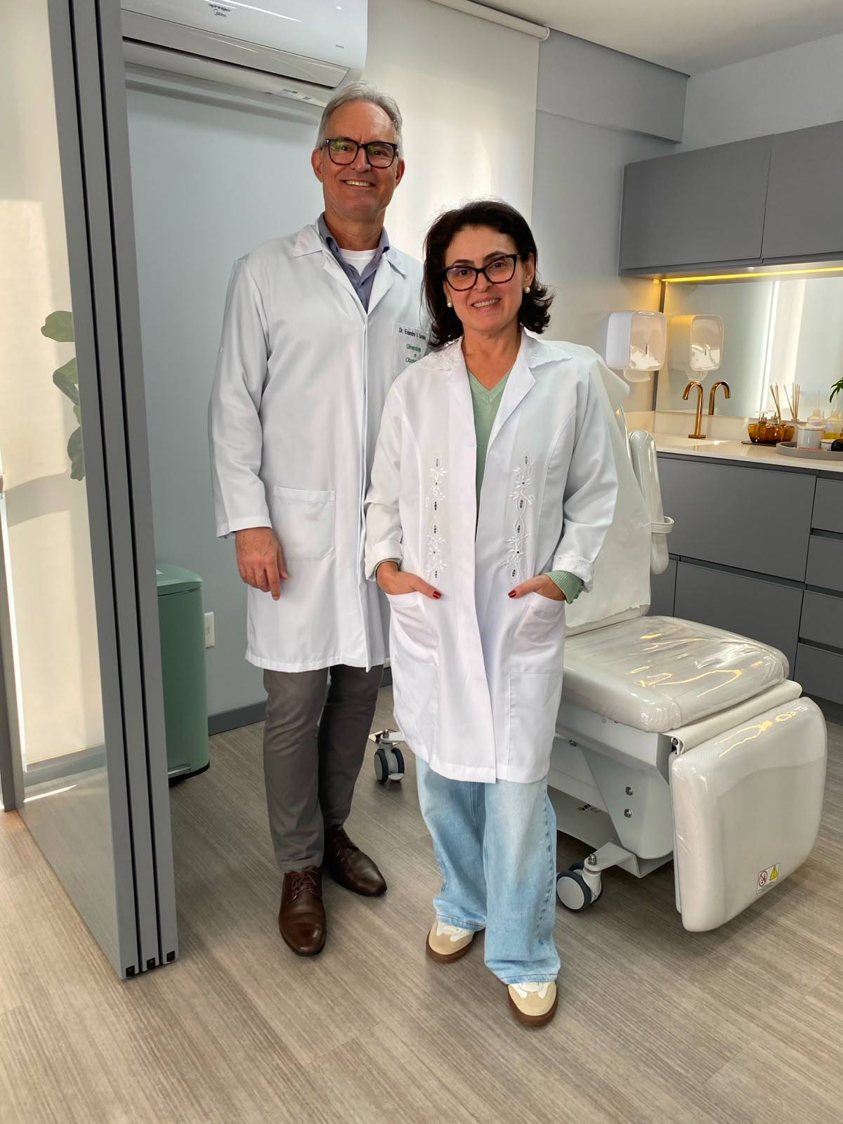 Dr. Evandro e a enfermeira Márlen, de jaleco, na sala de procedimentos do consultório